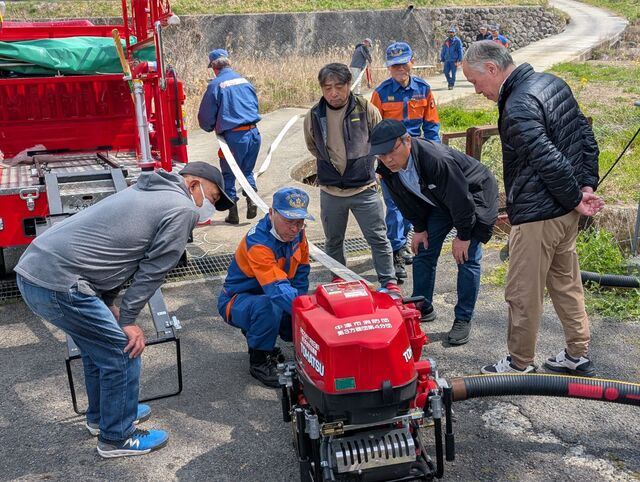 消防団員からポンプの説明を受ける地域住民と防災士
