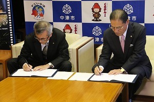 協定書に署名する奥塚市長と吉野理事長