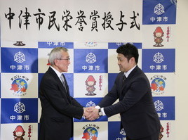 握手する西村氏と奥塚市長