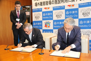 協定書に署名する奥塚市長と泉谷代表取締役社長