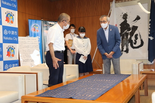 奥塚市長（写真右）に作品を説明する板橋さん（写真中央）