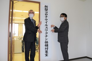 対策室の看板を設置する奥塚市長（写真左）と今冨生活保健部長