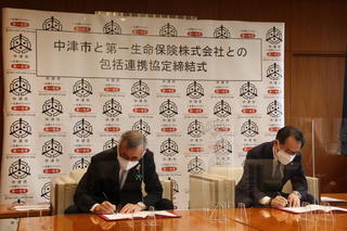 協定書に署名する奥塚市長（写真左）