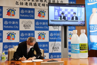 協定書に署名する奥塚市長（写真左）