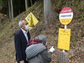 バス停のかかしを見る奥塚市長