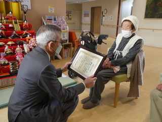 お祝い状を渡す奥塚市長（写真左）